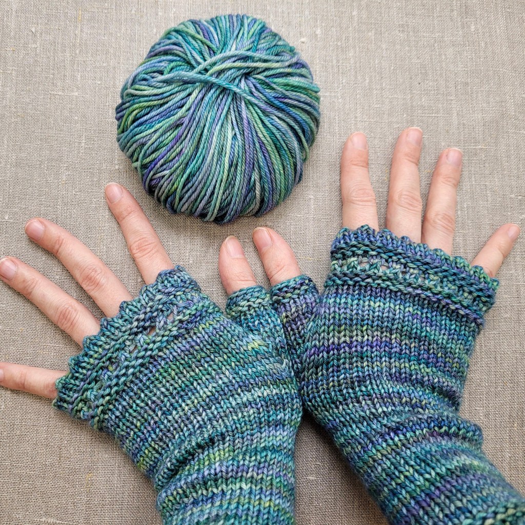 Et par hænder i de dejlige Pulsvarmere og det garn, der blev til overs