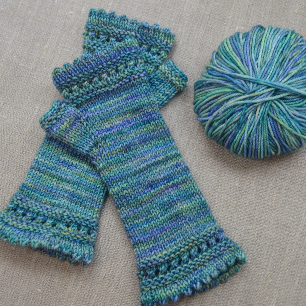 Pulsvarmere uden hænder i, strikket i malabrigo arroyo i farven indiecita. Et garnnøgle ved siden af.